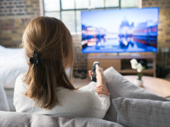 Woman relaxing at home watching tv and holding the remote control