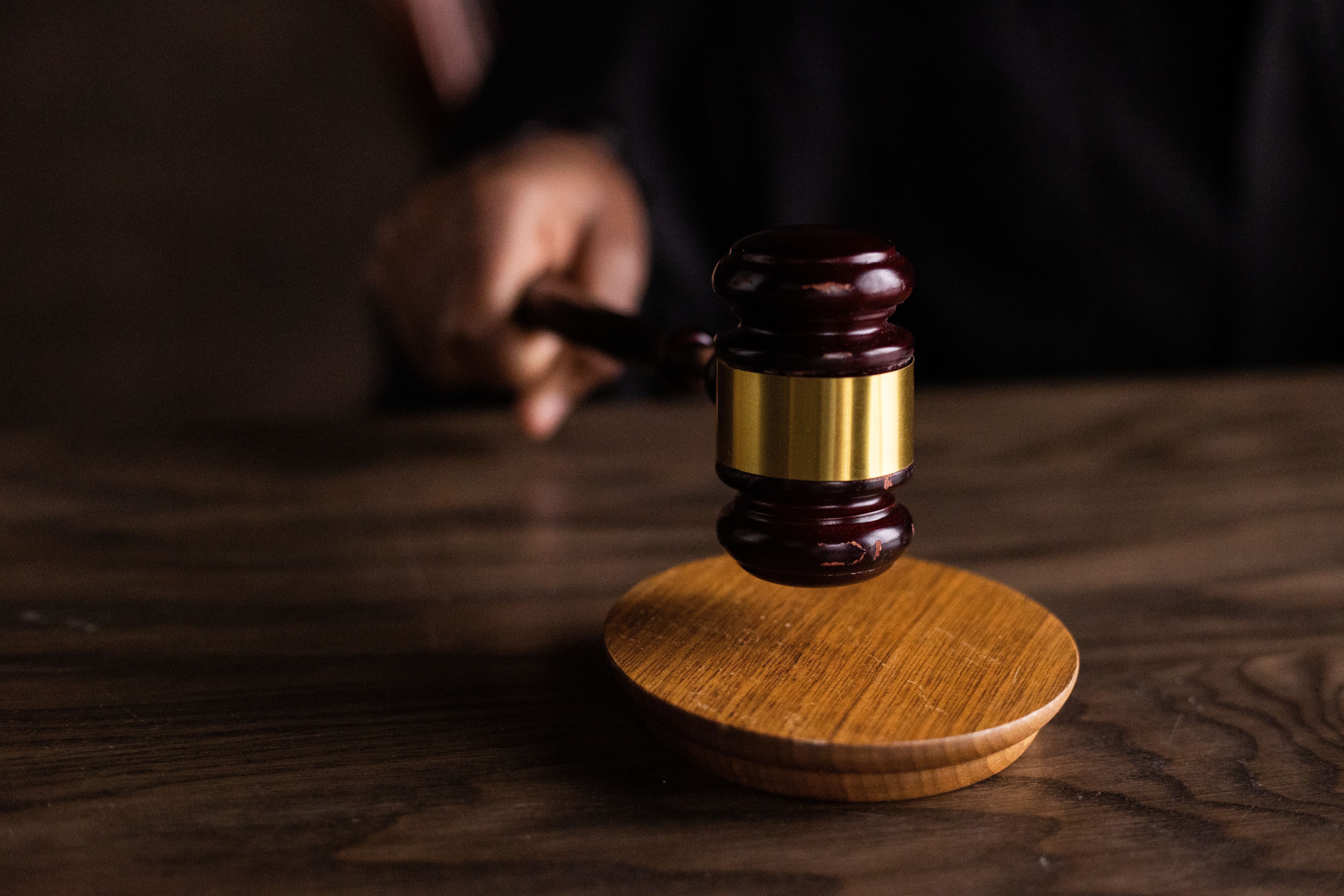 Gavel striking a sound block in a courtroom setting, representing legal authority
