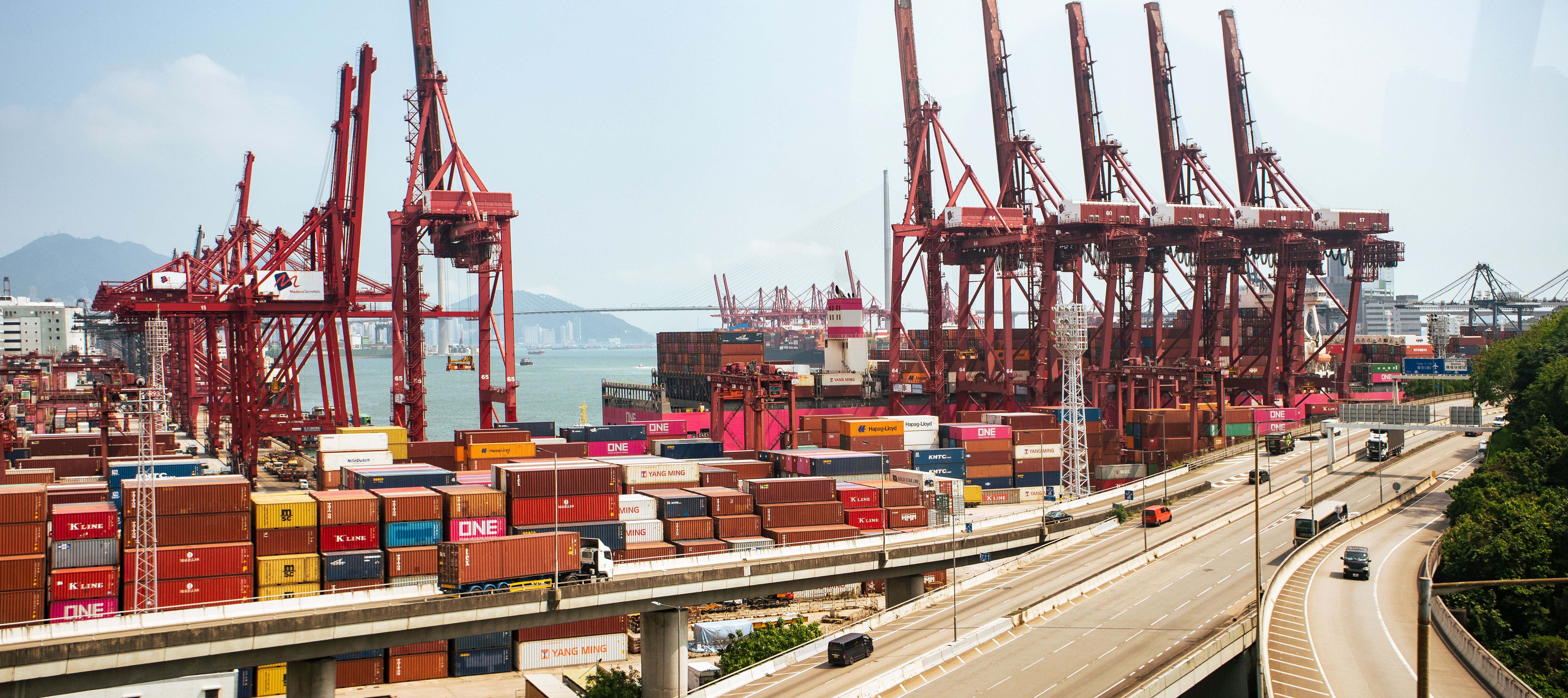 Hong Kong shipping port with red cranes and stacked cargo containers