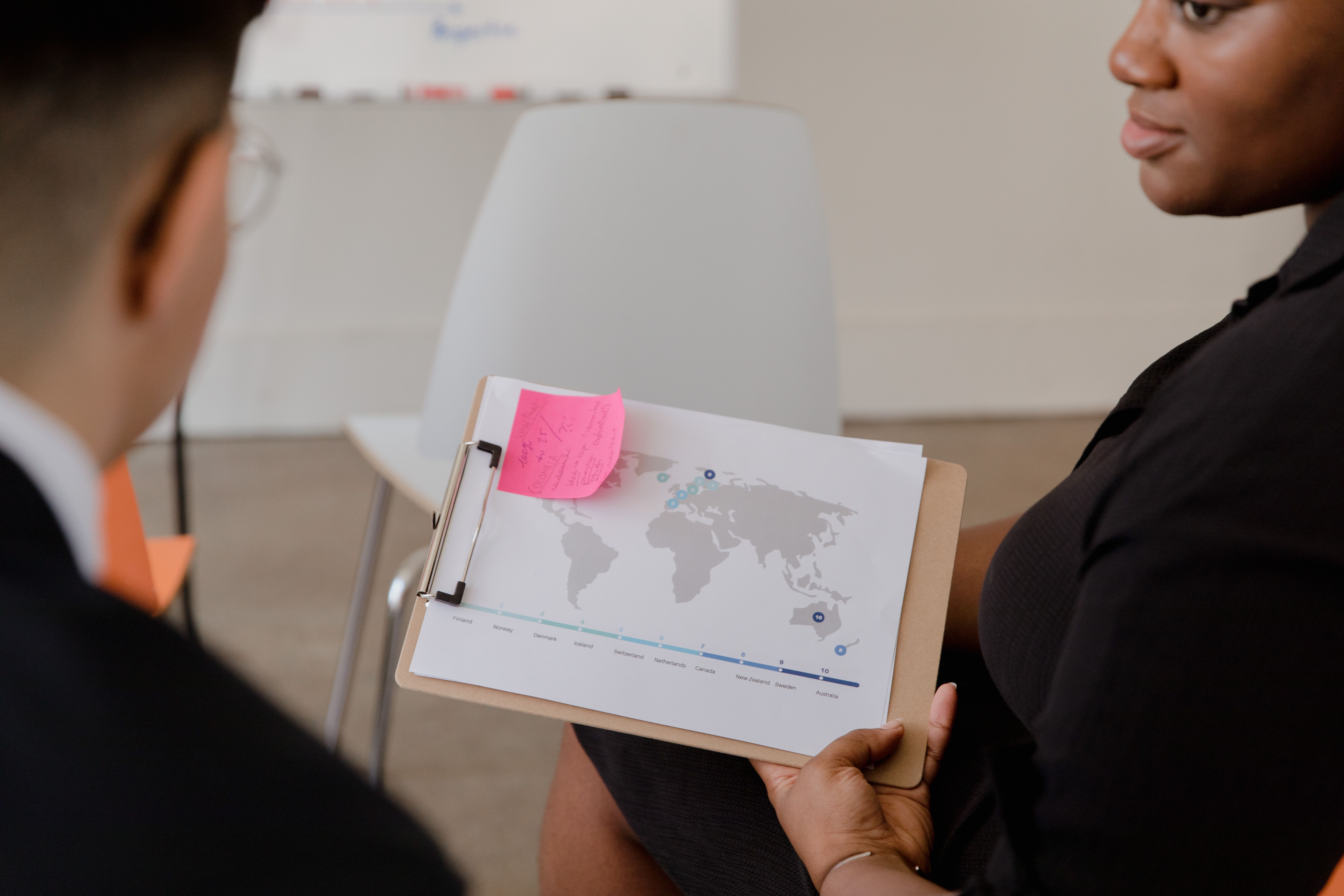 Professional discussion with a world map and data visualization on a clipboard