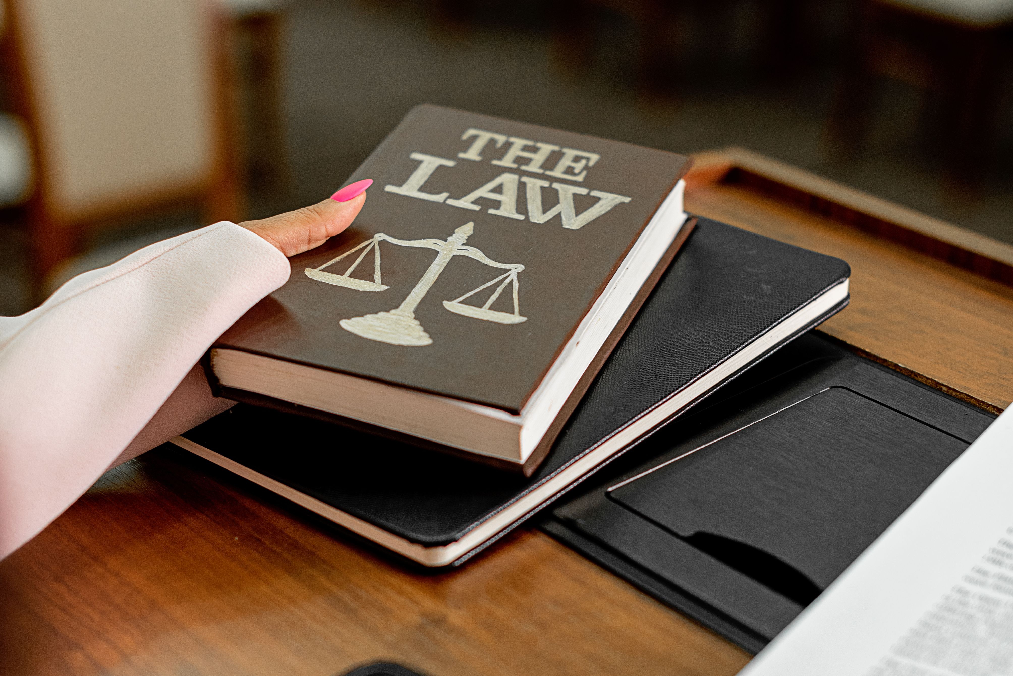 Law book titled 'The Law' on a wooden desk with scales of justice, symbolizing legal claims