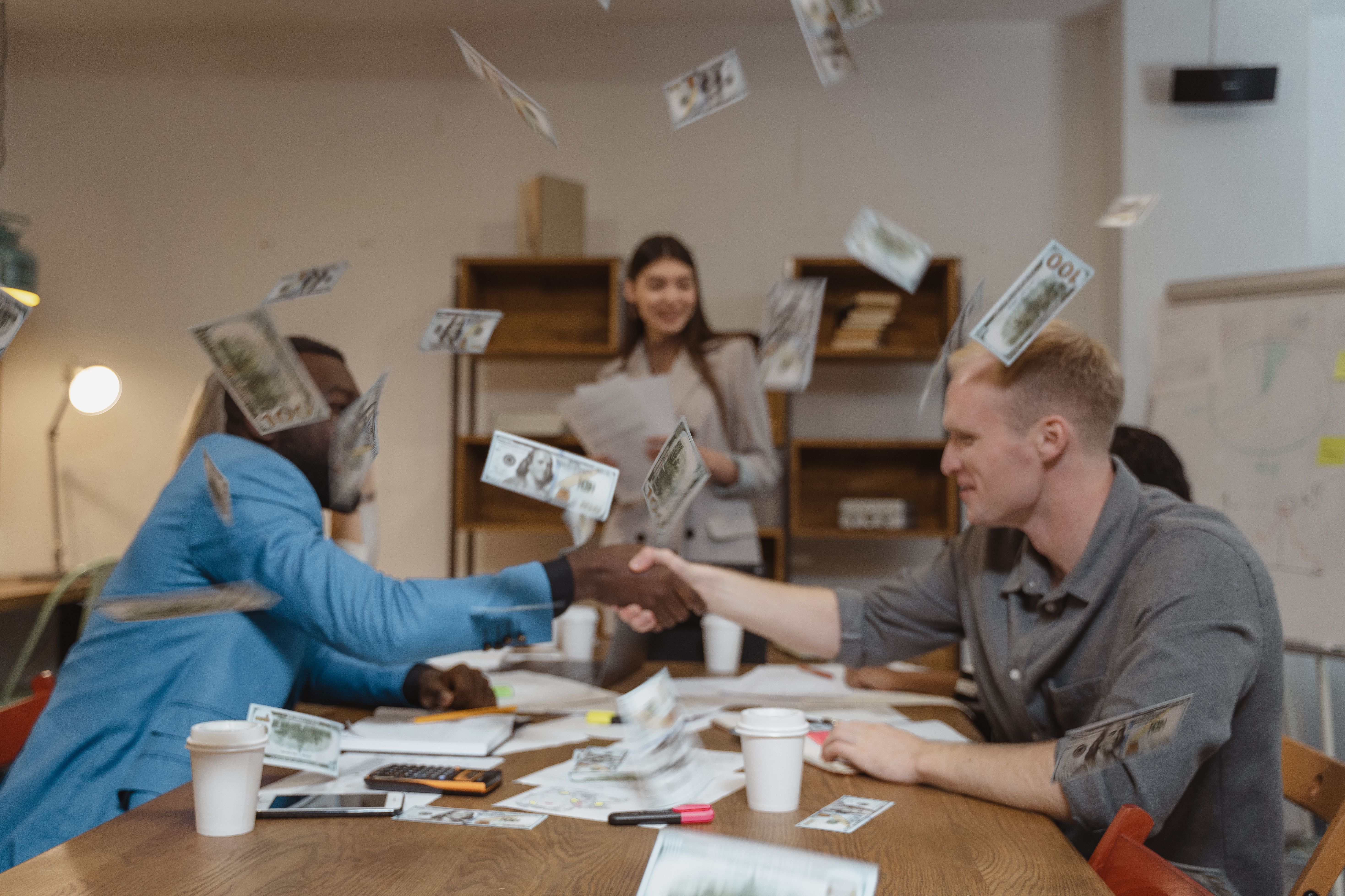 Business professionals shaking hands amid falling money, symbolizing a litigation funding investment